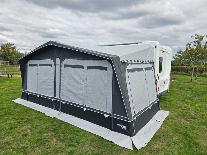 Camptech Westminster CS caravan awning with front canopy extension set up on a grassy campsite.