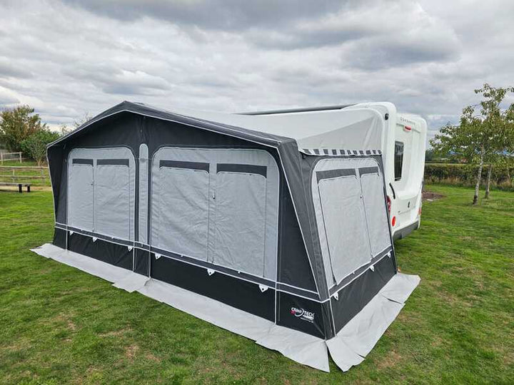 Camptech Westminster CS caravan awning with front canopy extension set up on a grassy campsite.