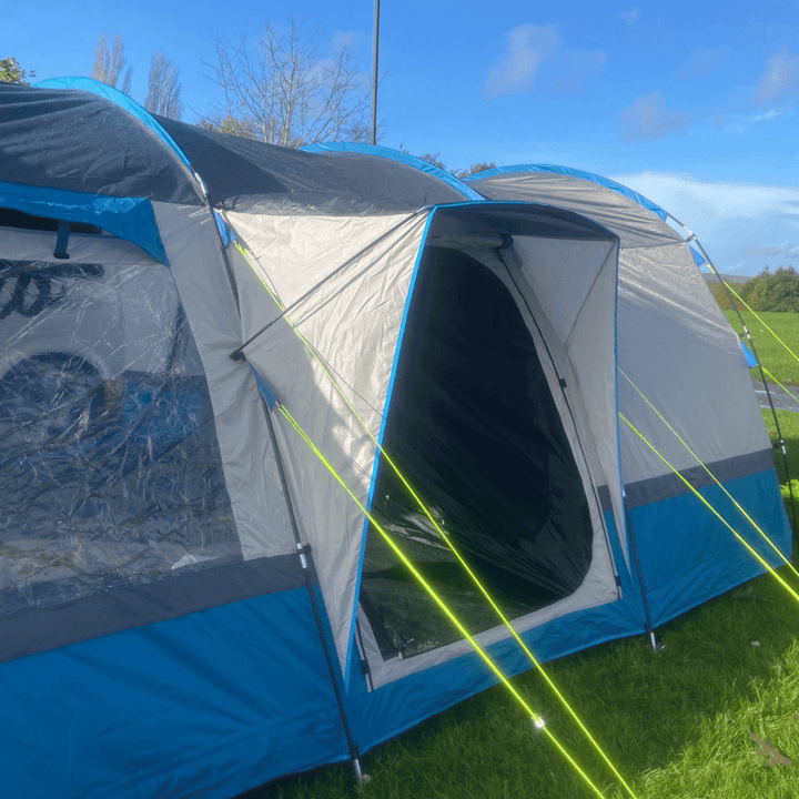 Blue and grey OLPRO Cocoon V2 campervan awning set up on grass under a clear sky.