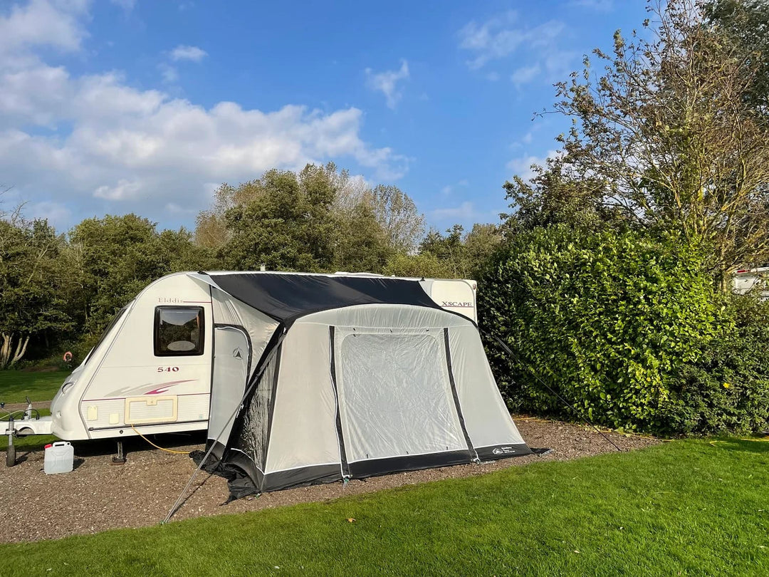 SunnCamp Dash Air 260 SC awning attached to a white caravan, showing the front and side profile with transparent windows and dark trim.