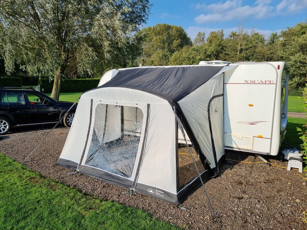 SunnCamp Dash Air 260 SC inflatable caravan awning viewed from the front, showcasing its transparent window panels, grey fabric walls, black roof section, and groundsheet.