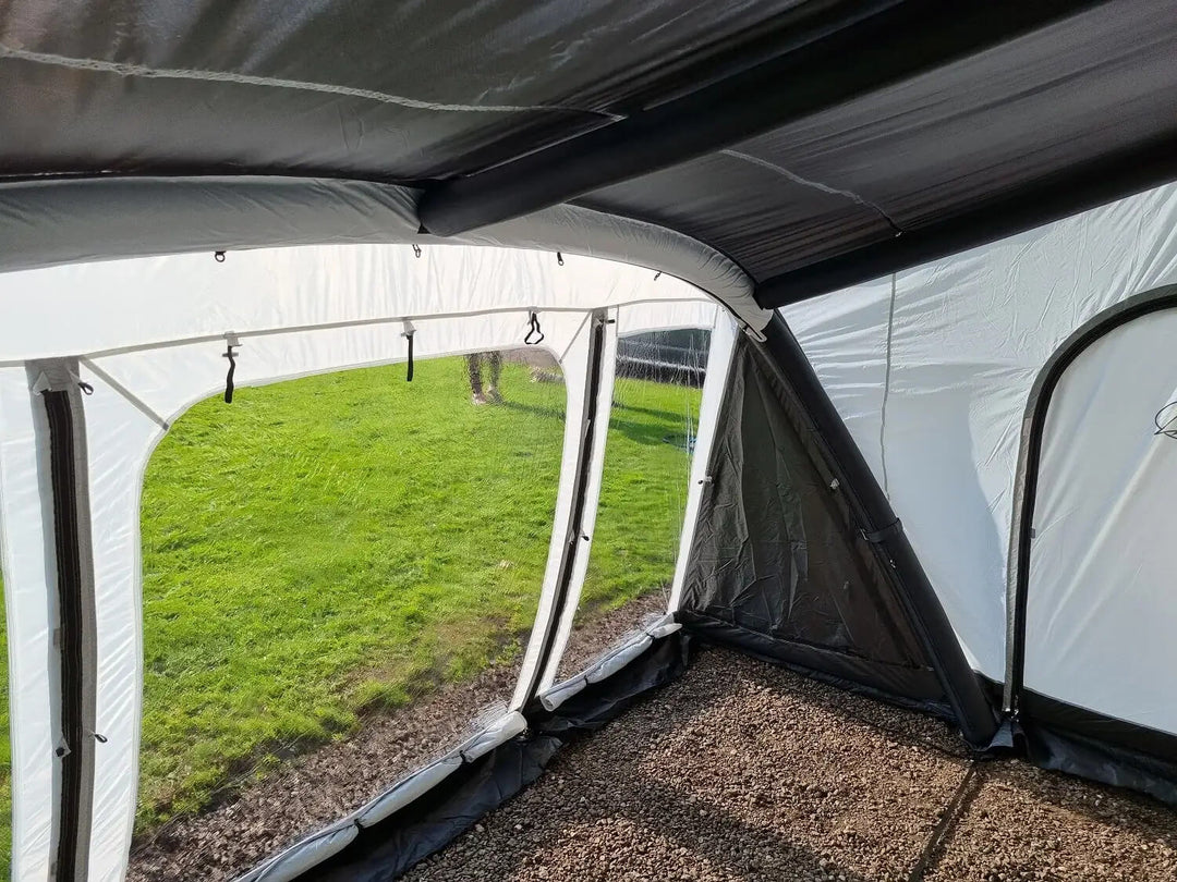 Inside view of the SunnCamp Dash Air 390 SC caravan awning, highlighting the transparent side windows, inflatable support beams, grey fabric walls and enclosed layout.