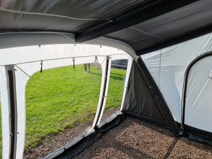 Inside view of the SunnCamp Dash Air 390 SC caravan awning, highlighting the transparent side windows, inflatable support beams, grey fabric walls and enclosed layout.