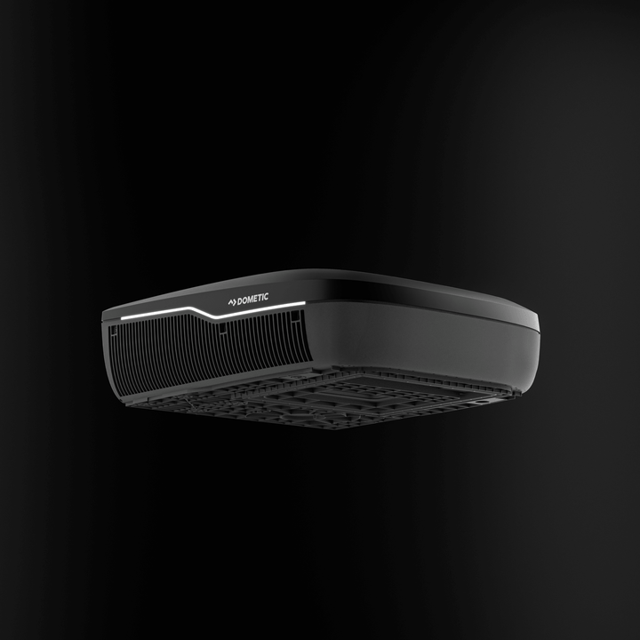 Underside angled view of the black Dometic FreshJet FJX7 2200 rooftop air conditioner, showing sleek base and grill design, on a black background.