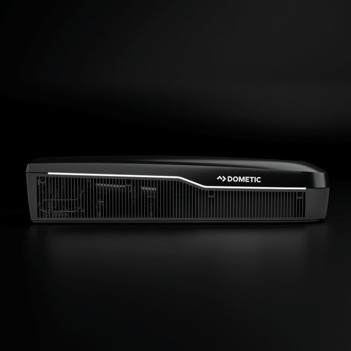 Side profile of the Dometic FreshJet FJX7 3000 in black. Features a lit LED strip and bold Dometic logo, with horizontal vents in a plain black background.