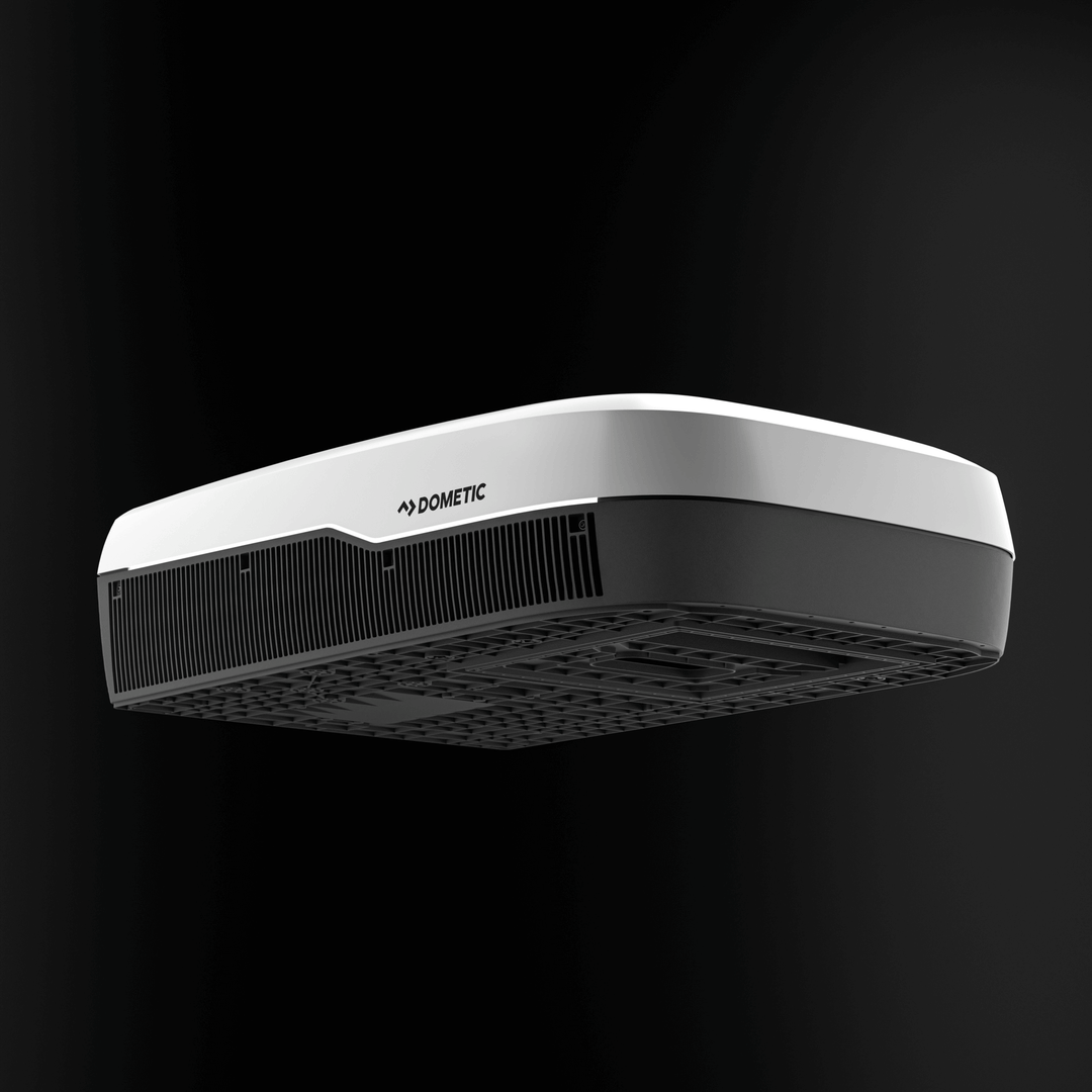 Low-angle front view of the white Dometic FreshJet FJX7 3500 Inverter unit. Features wide intake vents and contoured aerodynamic body, with a black background."