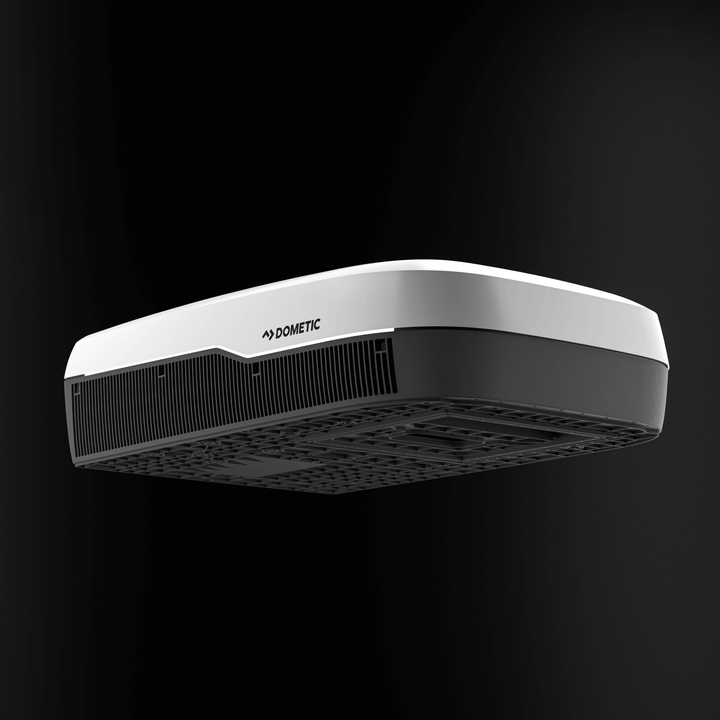 Low-angle front view of the white Dometic FreshJet FJX7 3500 Inverter unit. Features wide intake vents and contoured aerodynamic body, with a black background."