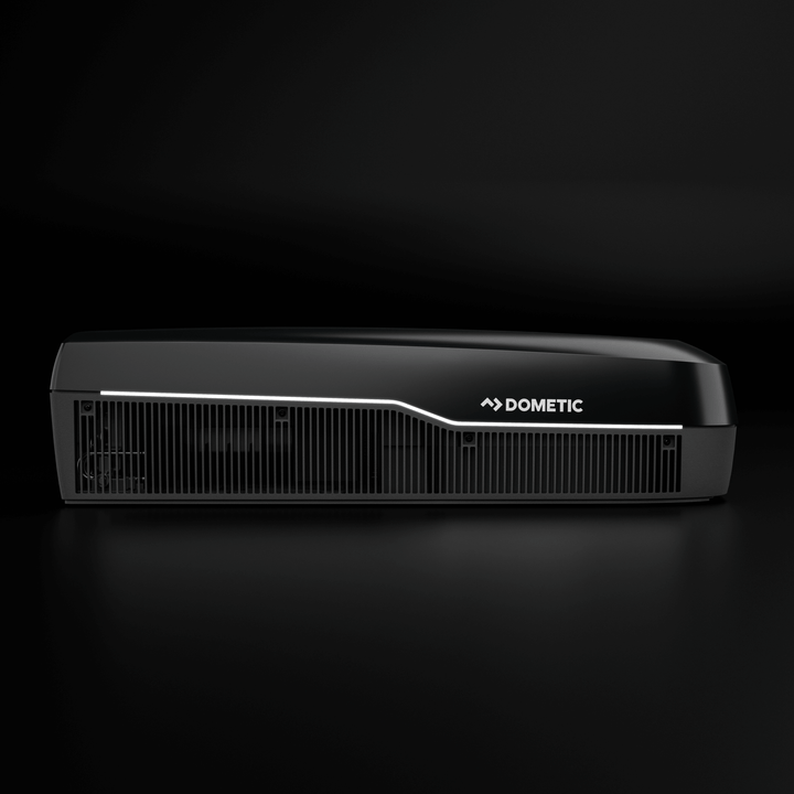 Side profile of the black Dometic FreshJet FJX7 3500 rooftop air conditioner. The unit has a sleek LED trim, horizontal vent design, and bold Dometic branding, on a black plain background.