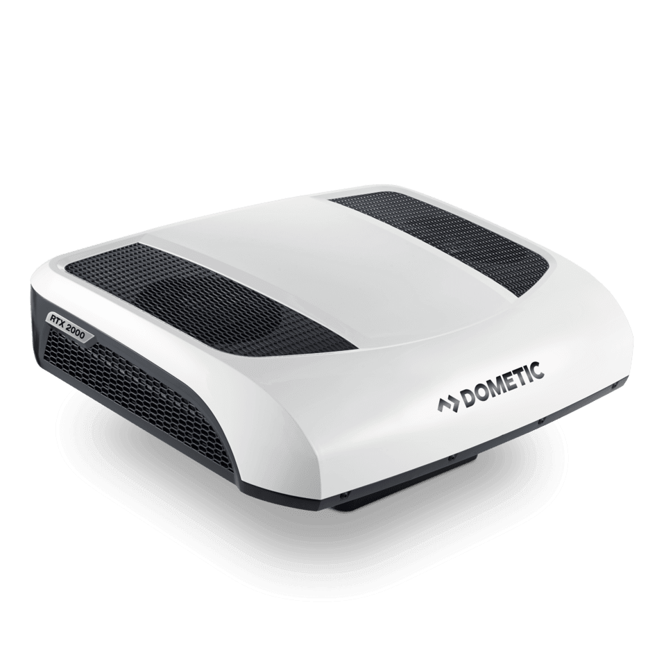 High-angle front-left view of the Dometic CoolAir RTX 2000 12V air conditioner. The unit has a sleek white top housing, two black mesh vent panels, and subtle curves for low drag. Visible RTX 2000 branding on side vent, on a transparent background.
