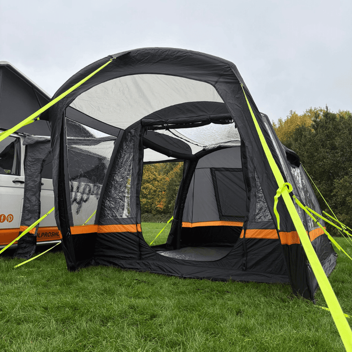Inflatable OLPRO Hanley Breeze awning attached to a campervan on a grassy field.