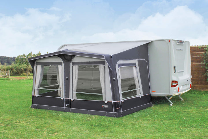 Camptech Duke DL air awning attached to a white caravan on a grassy campsite with cloudy sky background.