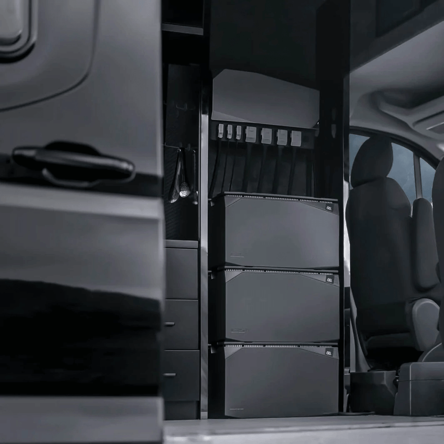 EcoFlow 5kWh Power Kit installed inside a camper van, featuring three vertically stacked batteries beneath the Power Hub, with a drawer system and passenger seat visible in the background