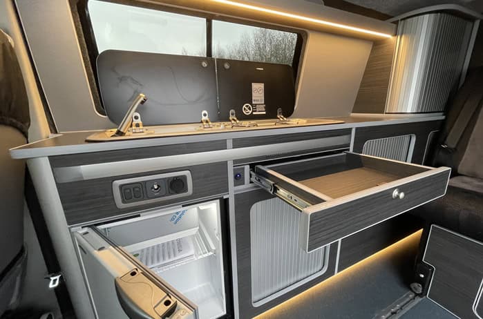 Ford Transit Custom Campervan Kitchen Unit kitchen layout with pull-out drawer extended and fridge door open inside camper van.