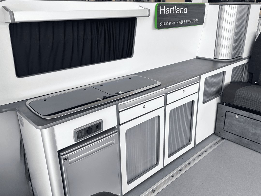 Ford Transit Custom Campervan Kitchen Unit white gloss full-length kitchen pod with ribbed cabinet doors and integrated fridge inside van interior.