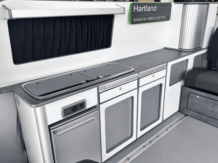 Ford Transit Custom Campervan Kitchen Unit white gloss full-length kitchen pod with ribbed cabinet doors and integrated fridge inside van interior.