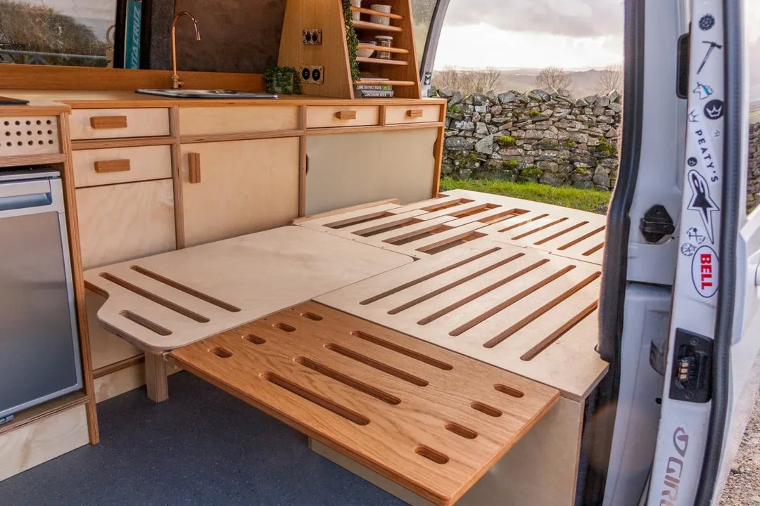 Campervan Bivi L Shaped Bed featured in a full campervan furniture conversion with pop top roof and modern wood interior finish.