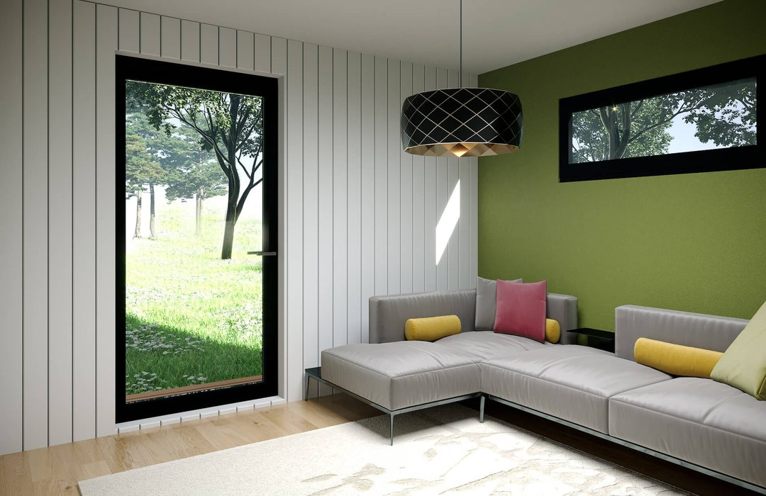 Interior view of a glamping pod living space with large window, corner sofa with colourful pillows, and modern lighting.
