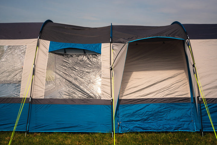 Front and side panels of the OLPRO Cocoon V2 awning showing clear windows and entrance, set up on grass.