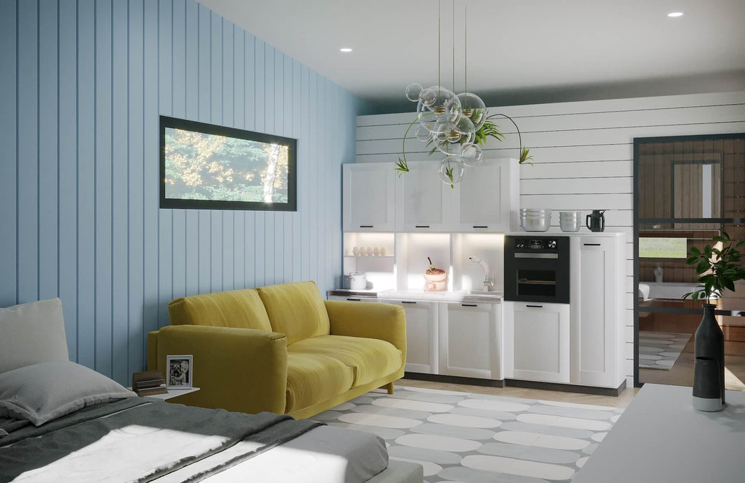 Bright and airy open-plan tiny home kitchen with white cabinets, yellow sofa, bed, and glass pendant lighting.