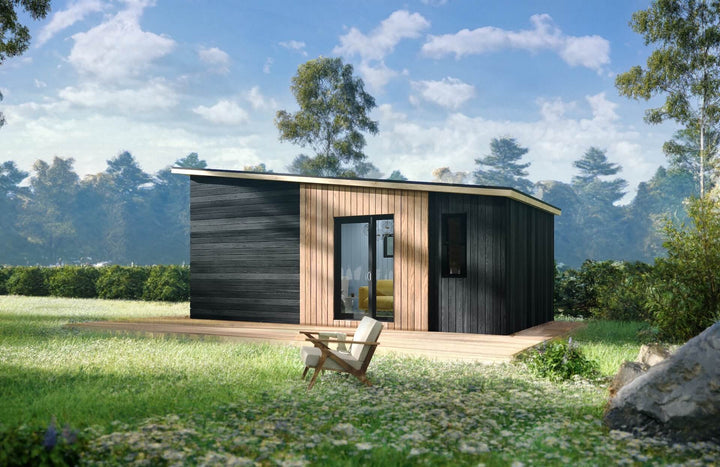 Angle view of a tiny home in a lush outdoor setting, showing its clean wood-clad exterior and a single lounge chair outside.
