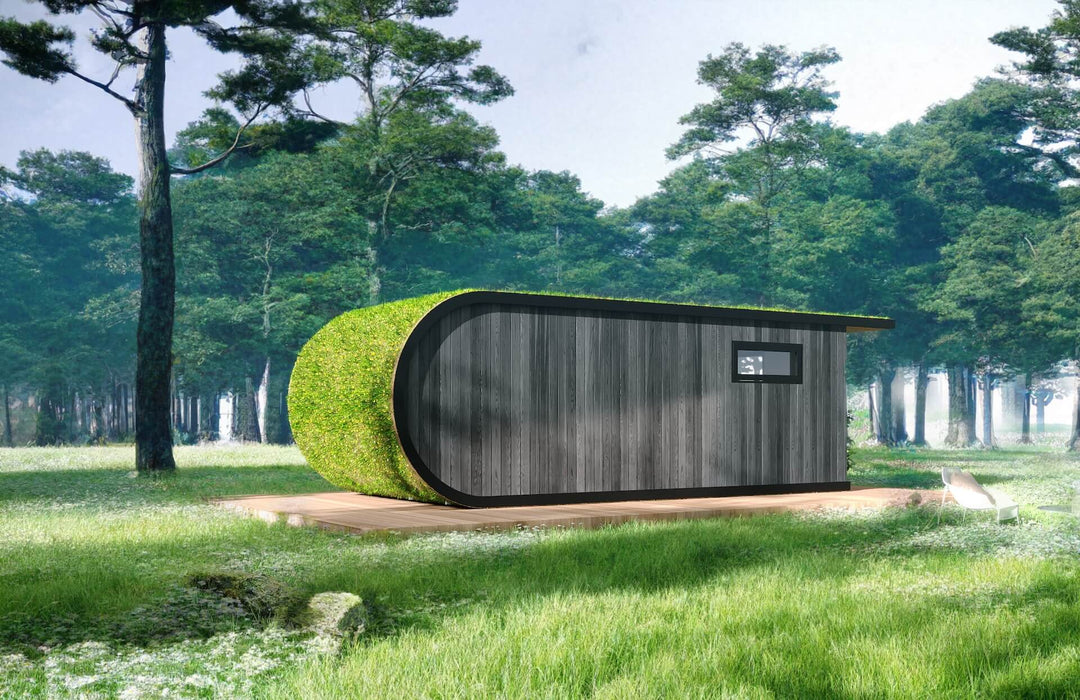 Back view of a curved black-clad glamping pod set on a wooden platform in a forest meadow.