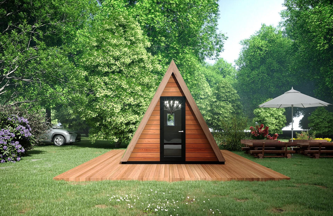 Symmetrical front view of the A-frame glamping pod on a wooden platform, set in a forest clearing with outdoor seating nearby.