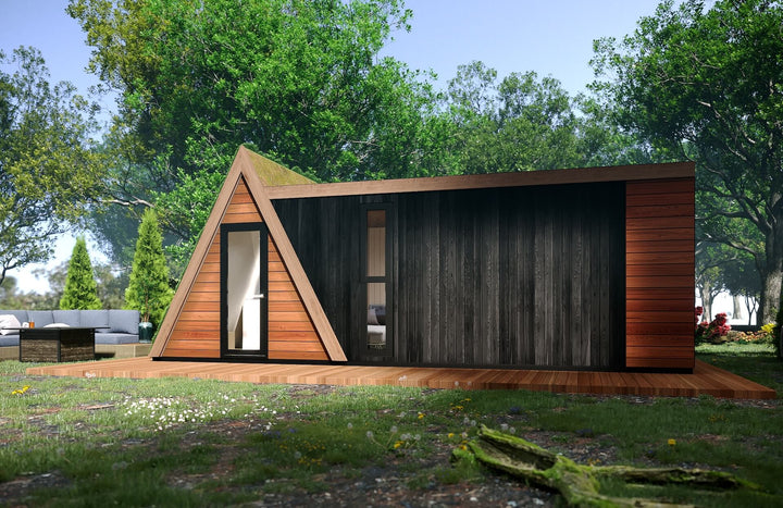 Side view of the unit with a mossy green roof and mixed wood cladding, set on a wooden deck in a forest setting.