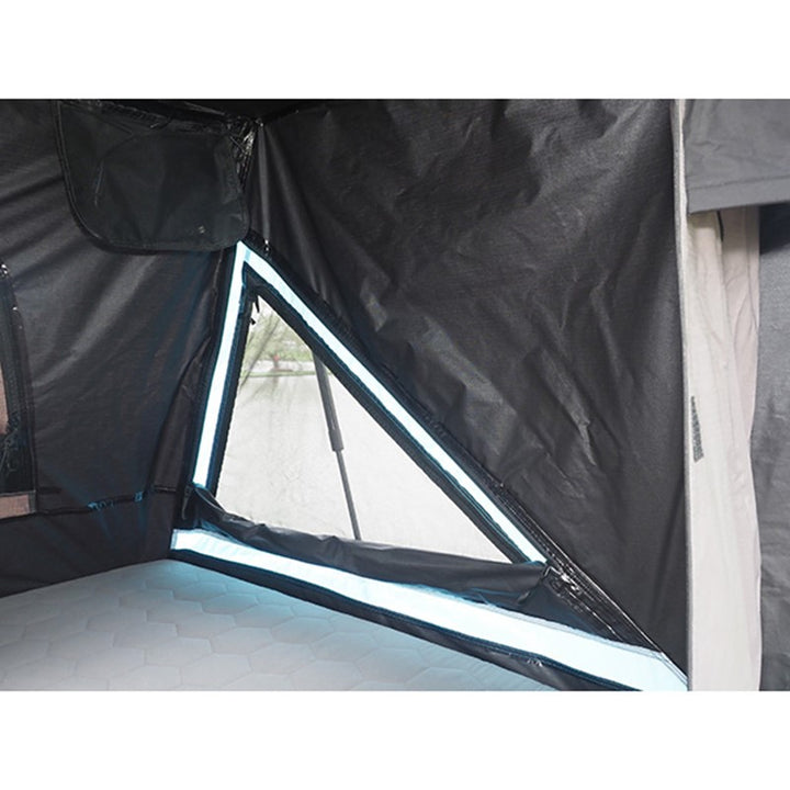 Interior view of Skypod rooftop tent showing mattress and triangular window with blue trim.