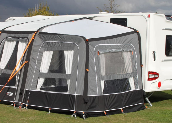 Camptech Starline Elite Infinity Pod in grey and black attached to a caravan on a grassy background.