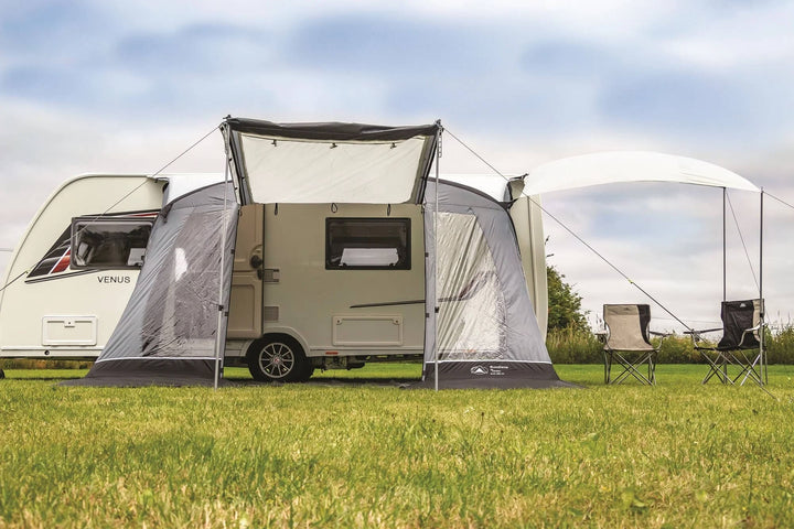 SunnCamp Swift Air 390 SC awning attached to a white Venus caravan, viewed from the rear with the front canopy extended and camping chairs set up outside.