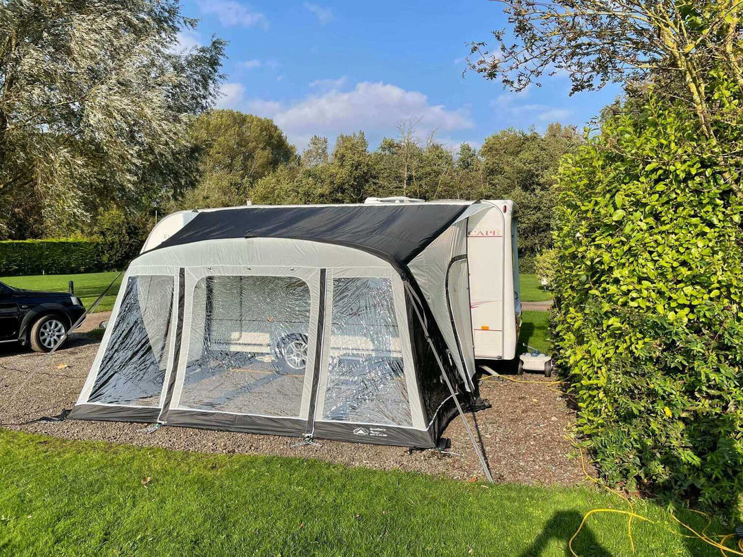 SunnCamp Dash Air 390 SC awning viewed from the front, showcasing its large clear windows, grey exterior, dark roof and secure guy ropes.