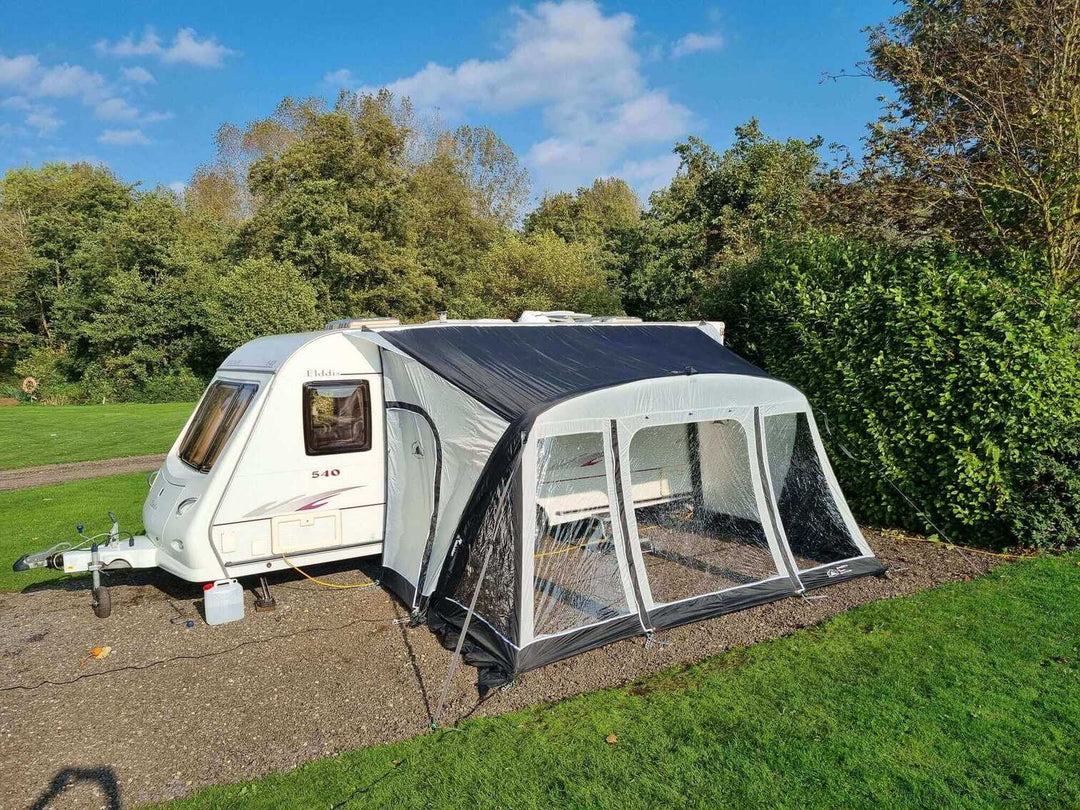 SunnCamp Dash Air 390 SC awning attached to a white caravan, showing the front and side canopy with transparent windows and black edging.