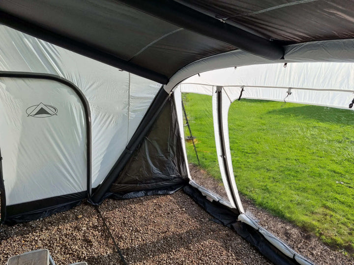 Interior view of the SunnCamp Dash Air 390 SC awning, showing its dark inflatable roof beams, grey walls, clear window panels and spacious gravel-floored interior.