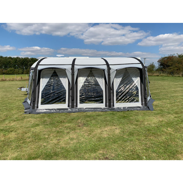 A Sunncamp Icon Air Awning photographed from a side angle on green grass, showing the full structure with four connected sections and black framework