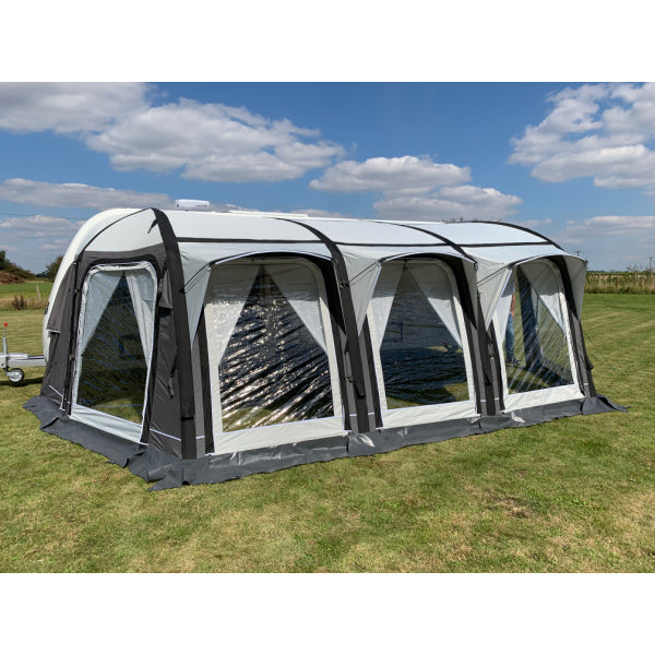 A Sunncamp Icon Air Awning captured from the side, showing the full length attachment to a caravan with four distinct sections on well-maintained grass