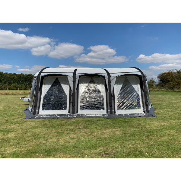 A Sunncamp Icon Air Caravan Awning photographed at an angle showing the sleek design of four sections with black air beams and white panels on a grass field