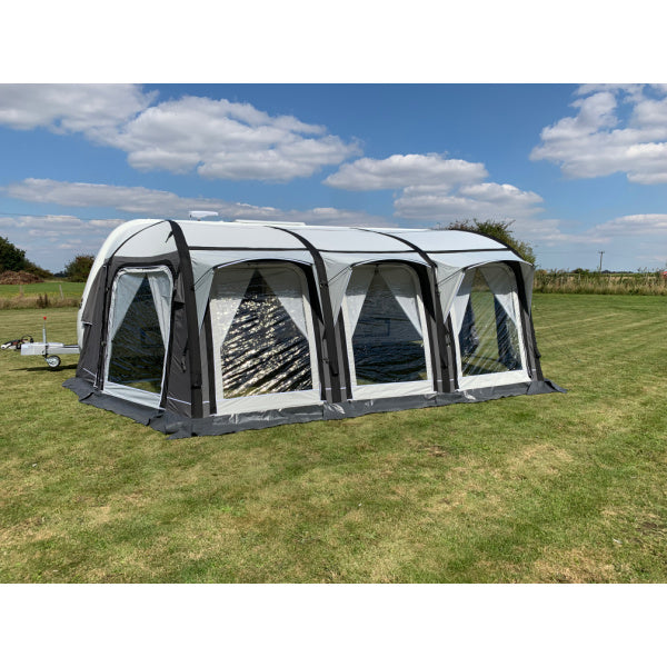 A Sunncamp Icon Air Caravan Awning shown in profile, displaying the four-section design with white panels and black support structure on a sunny day