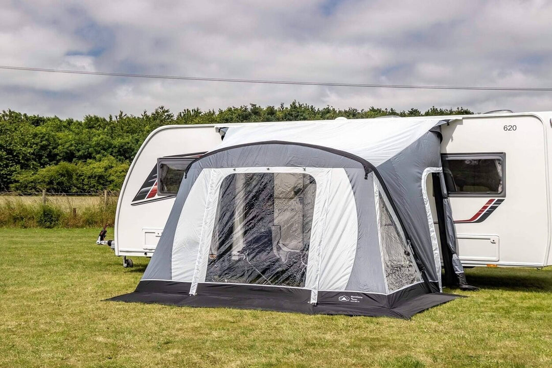SunnCamp Swift Air 260 SC awning with a large transparent front window, grey and white fabric panels, and a black groundsheet attached to a white caravan.