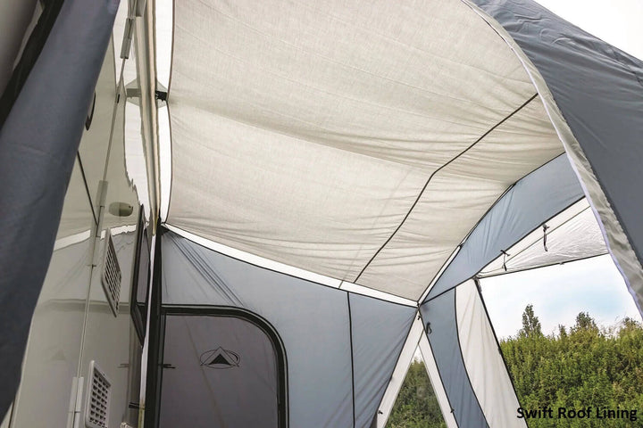 SunnCamp Swift Air 220 SC inner roof lining showing the light-coloured ceiling fabric and supporting seams inside the awning, with the caravan wall and green hedges visible in the background.