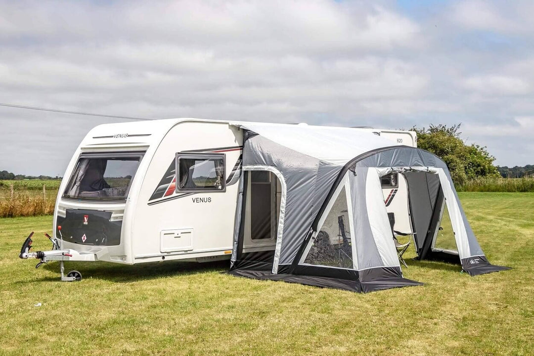 SunnCamp Swift Air 260 SC awning attached to a white Venus caravan, featuring clear window panels, an open front entrance, and a covered outdoor seating area on a grassy campsite.