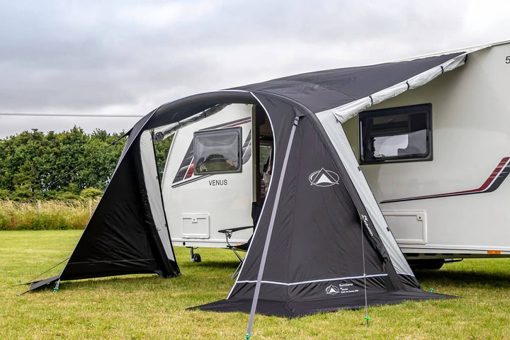 Black and grey SunnCamp Swift Air 260 caravan awning with large clear windows and an arched entrance, attached to a white caravan on a grassy campsite.