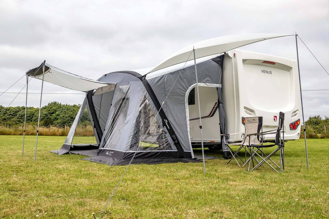 SunnCamp Swift Air 390 SC caravan awning with an extended front canopy supported by poles, providing a shaded outdoor seating area beside the caravan.