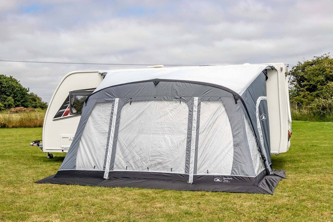 SunnCamp Swift Air 390 SC awning with its front panels fully closed, featuring large clear windows and grey fabric borders attached to a white caravan.