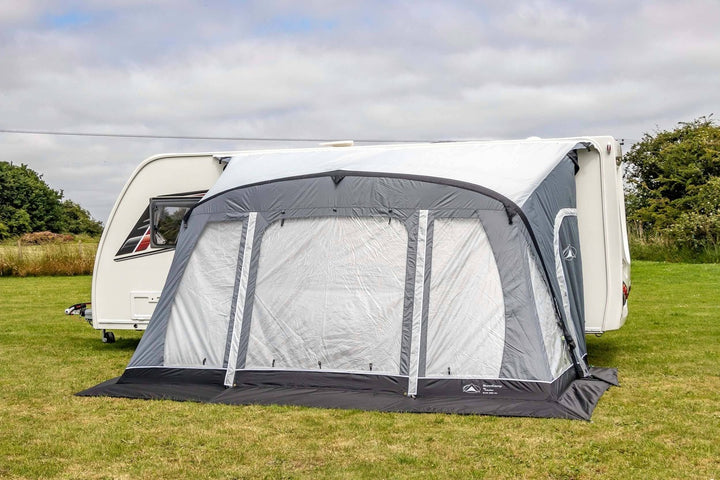 SunnCamp Swift Air 390 SC awning with its front panels fully closed, featuring large clear windows and grey fabric borders attached to a white caravan.