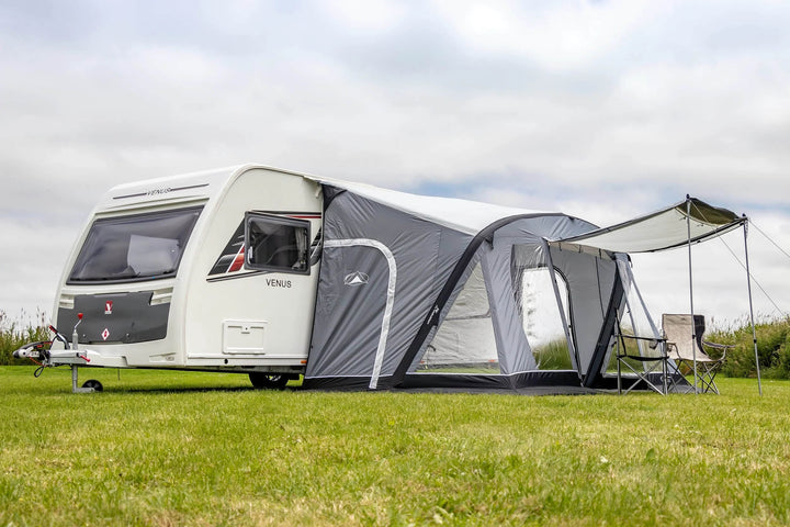 SunnCamp Swift Air 390 SC awning with an extended buckle-fit side sun canopy providing additional shade beside a white caravan.