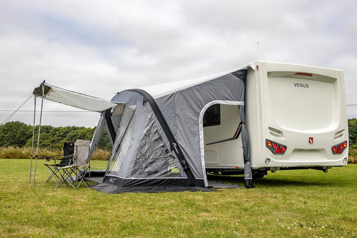 SunnCamp Swift Air 390 SC inflatable caravan awning with transparent front windows, grey side panels and a black groundsheet on a grassy campsite.