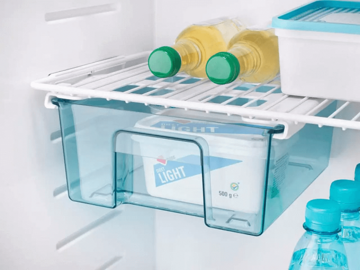 Thetford THET.FRIDGE N4141A FLAT FRAMED – Interior fridge view featuring a translucent blue drawer with packaged dairy products, white wire shelf above.