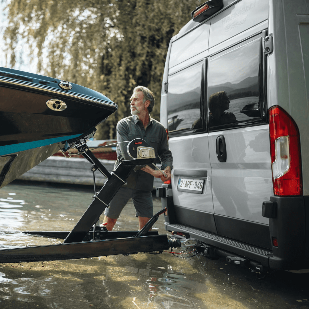 Man attaching boat trailer to Thule Veloswing towbar on a lakeside background.