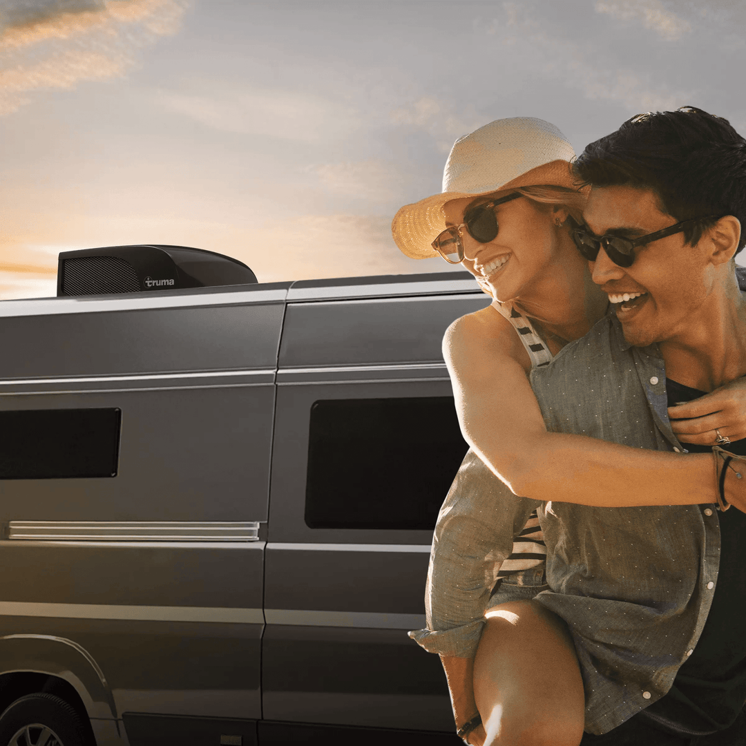 Couple enjoying sunset beside a camper van equipped with a Truma Aventa Compact Plus rooftop air conditioner in black finish.