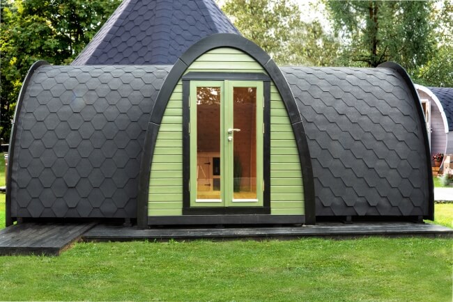 Full front view of the Viking Industrier 2.4 x 5.9m Camping Pod with Side Entrance featuring green siding and black roof on a grassy outdoor background.